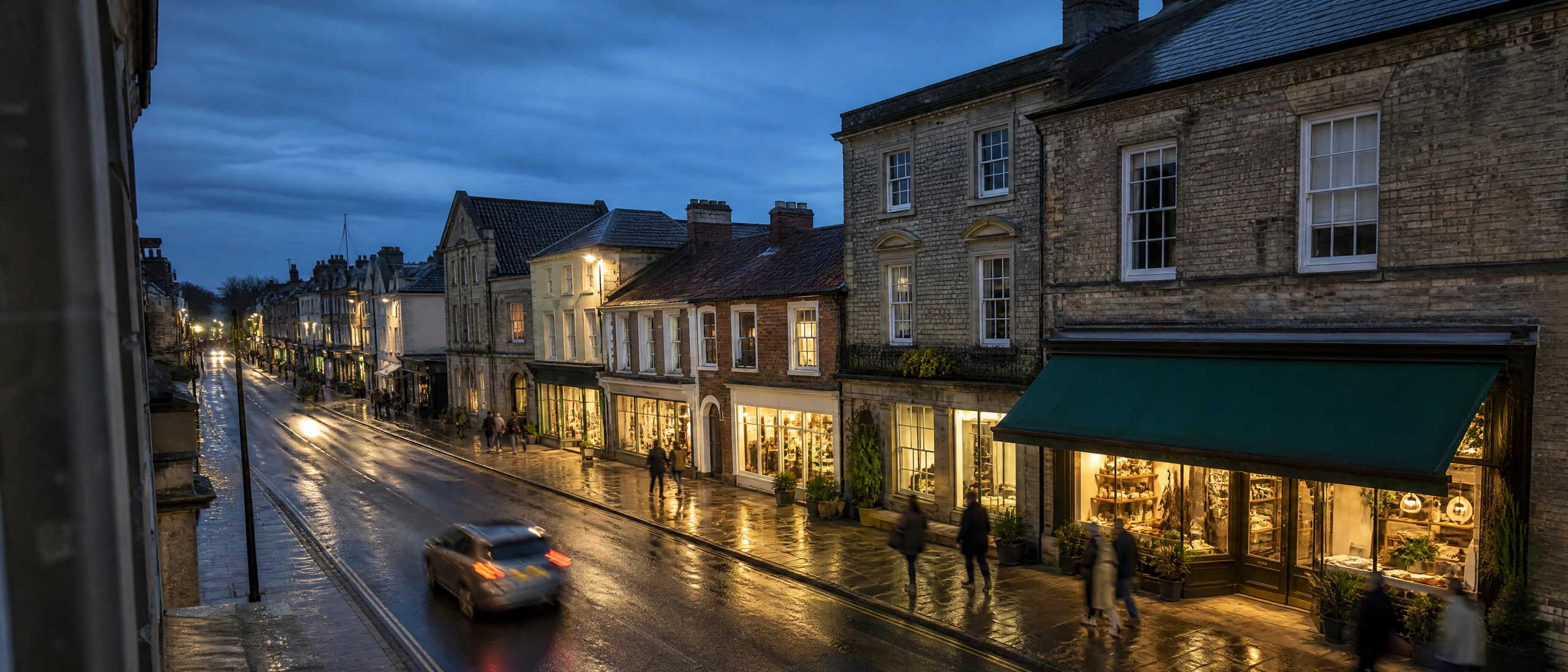 A British high street at dusk, pedestrians anonymous in motion blur